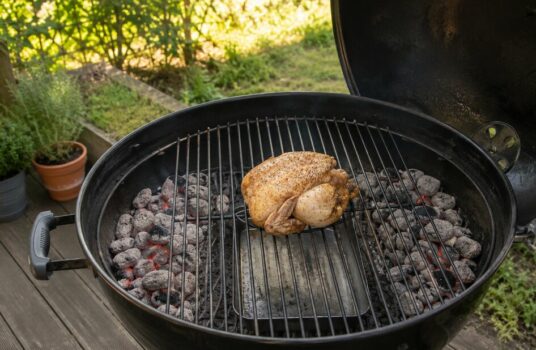 Poulet placé au centre d’un barbecue à charbon, entre deux zones de braises disposées pour une cuisson indirecte