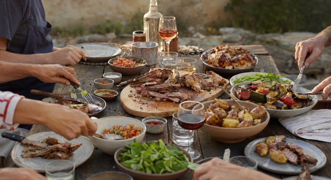 Grande tablée familiale garnie de viandes grillées, de poulet, de légumes et de pommes de terre à partager