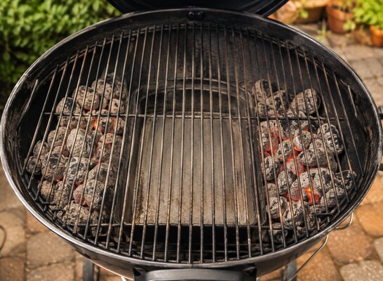 Braises disposées sur les côtés d’un barbecue à charbon pour créer une zone de cuisson indirecte au centre